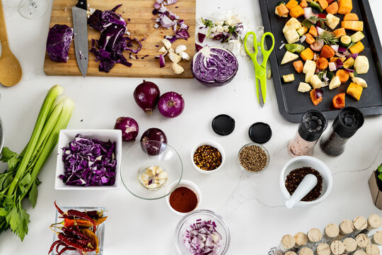 Overhead view of vegetables, seasonings in bowls and flasks with spices on table