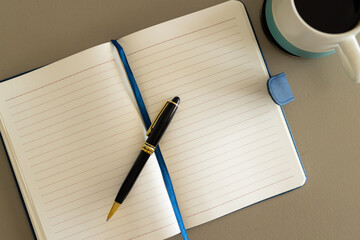 Overhead view of notebook, pen and cup of coffee on table