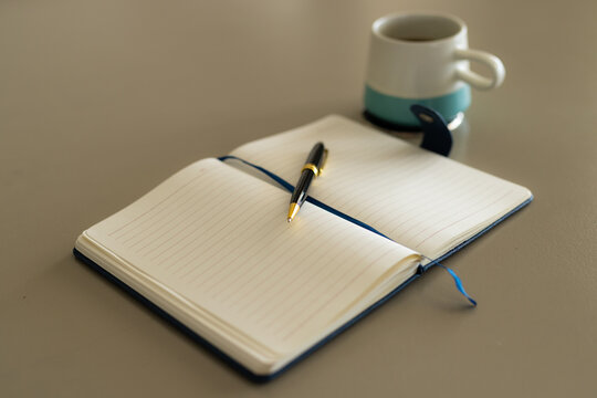 Close up of notebook, pen and cup of coffee on table