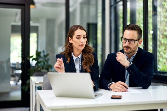 Female and male businesspeople sitting in front of the laptop at the office.
