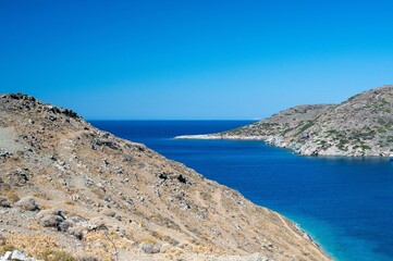 Picturesque landscape featuring a grassy hill rising above the serene waters, Kythnos island, Greece