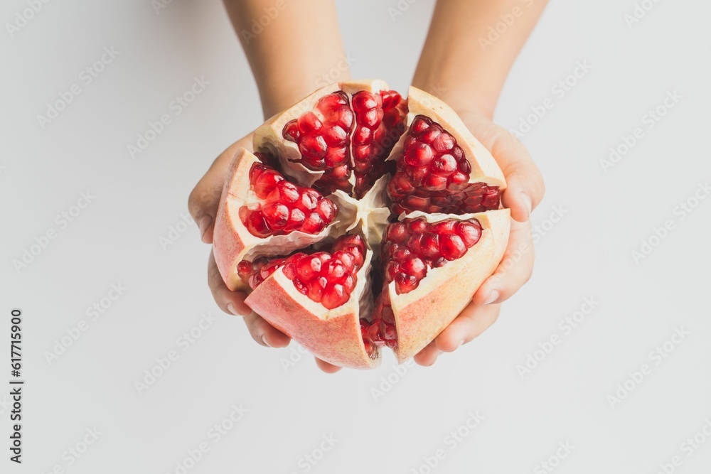 Poster Person's hand holding an open pomegranate on a white background