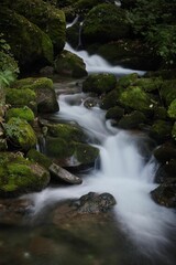 water runs down a river with mossy rocks on the side