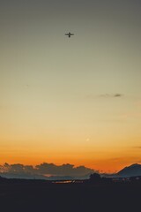 Commercial airplane flying over a city during sunset