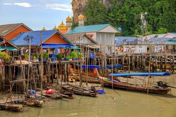 Scenic image of the waterfront with several stilted wooden houses and traditional boats moored