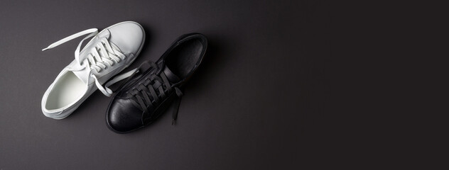 White and black leather shoes on a black background. sneakers with laces. New shoes. Horizontal image. Banner for insertion into site.