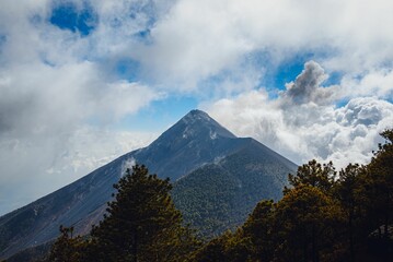 Fototapeta premium Dramatic view of El Fuego volcano in Antigua, Guatemala covered in white clouds