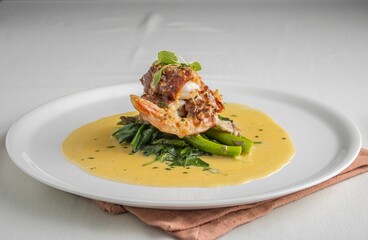 A gourmet seafood dish with creamy yellow sauce and greens
