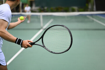 Tennis player serving tennis ball during a match on open court. Sport, fitness, training and active life concept