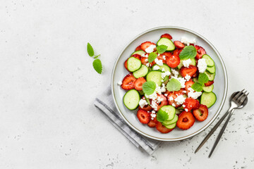 Low carb healthy cucumber strawberry goat cheese salad on plate. Top view, flat lay, copy space.
