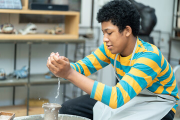 An African American boy embraces his artistic talents, passionately working with clay to create...