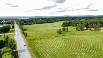 Aerial rural landscape featuring a vast field with green trees and a highway road