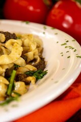 white plate topped with pasta and vegetables sitting on orange cloth