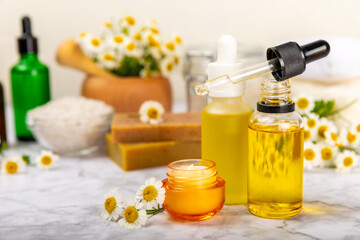 Chamomile Spa. Essential oil, sea salt, chamomile flowers, body cream and handmade soap. Natural herbal cosmetics with chamomile flowers on a textured background.Beauty concept. Cosmetic tube. 