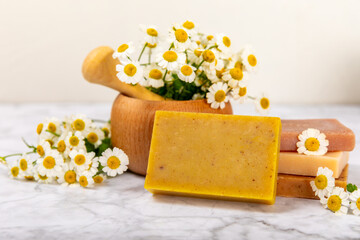Obraz na płótnie Canvas Natural homemade soap with chamomile flowers on a marble background. Spa procedure. Beauty concept. Body skin care. Place for text. copy space.