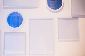 Many different sizes of blank photo frames on white wall