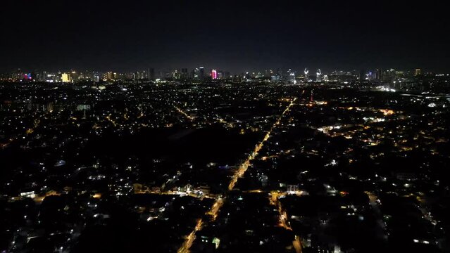 Drone view over dark cityscape with illuminated streets in Cainta, Philippines