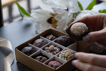 Chocolate craft candy in female hand and candy box