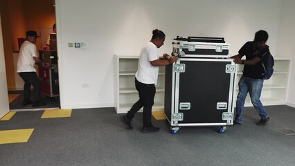 Men moving flight cases and boxes into an office space for a live streaming event
