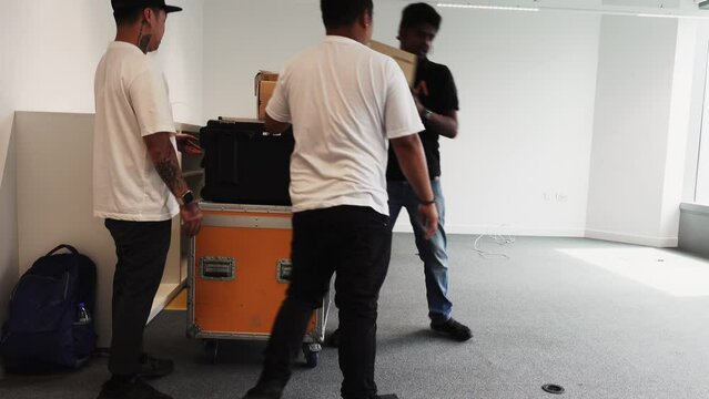 3 workers moving flight cases and boxes into an office space for a live streaming event
