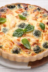 Delicious homemade quiche with salmon, broccoli and basil leaves on table