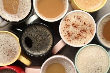 Many cups with different aromatic coffee on grey table, flat lay