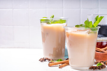 Thai Iced tea, asian indian masala spices drink with non-dairy coconut whipped milk, ice cubes and mint leaves, copy space