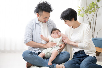 かわいい赤ちゃんとリビングで過ごす家族　目をこすって眠いねんねしそうな赤ちゃん