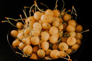 A group of ripe white cherries in a bowl rotating on a table 