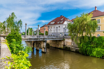 A view along the side of the River Ljubljanica towards the Shoemakers bridge in Ljubljana, Slovenia in summertime