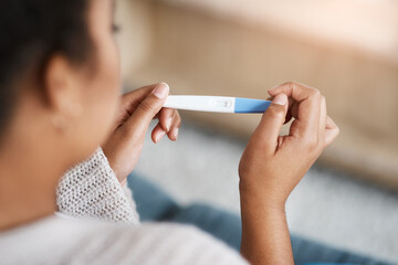 Pregnancy test, woman hands and waiting at home for results on a living room couch. House, female person and hand with testing stick to show pregnant sign while checking alone on lounge sofa