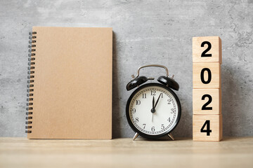 2024 Happy New Year with blank notebook, black retro alarm clock and wooden number. countdown, Resolution, Goals, Plan, Action and Mission Concept