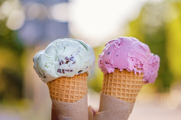 Two scoops of ice cream in hand. ice cream on a summer day outdoors.