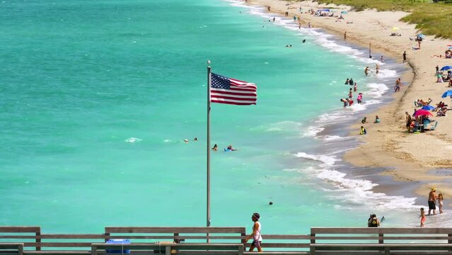 Famous Venice fishing pier and sandy beach in Florida. Many people enjoing vacation time bathing in warm gulf water and tanning under hot sun