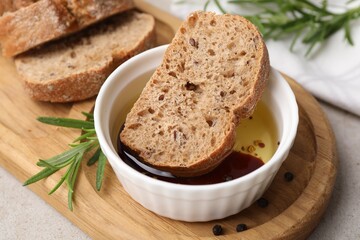 Bowl of organic balsamic vinegar with oil served with spices and bread slices on beige table, closeup