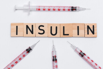 Napis insulina ułożony na białym tle, obok strzykawek insulinówek - obrazy, fototapety, plakaty