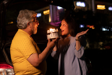 Happy Senior Citizen couple cutting birthday cake at night in the city