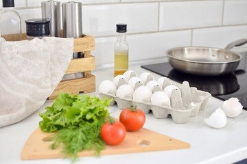 cooking breakfast.Egg,tomatoes,greens on the table near the stove.