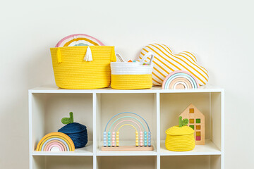 White shelving with rainbow wooden toys and colorful storage baskets. Interior design. Organizing...
