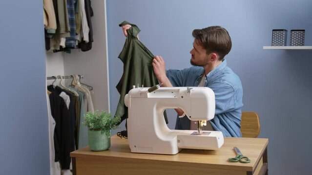 Upset caucasian man sew t-shirt by himself at home