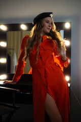 Fashion elegant woman posing in orange long coat and hat