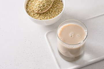 Alternative grain green buckwheat milk in glass on white background. Vegan plant based milk replacer. Close up. Copy space.