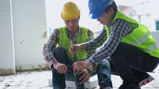 Engineer teaching worker for use electric jackhammer for perforator equipment making holes the floor to be strong at construction site, Concept of worker and residential building