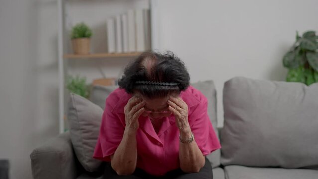 A senior woman who has a severe headache suffers from a stroke ,brain disease,patient holding head with her hand,suffering from senile dementia,memory disorders, confused old elderly with Alzheimer