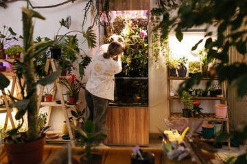 woman caring for a garden terrarium in a glass container