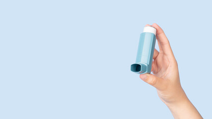 Hands holding asthma inhaler for relief asthma attack isolated blue background. Pharmaceutical products is used to prevent and treat wheezing and shortness of breath caused asthma or COPD. - obrazy, fototapety, plakaty
