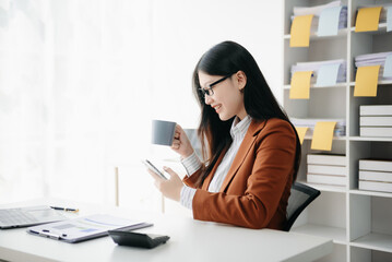 Confident Asian woman with a smile standing holding notepad and tablet at the modern office..