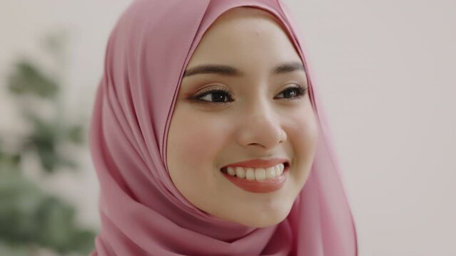 Closeup smiling face of a beautiful Asian Muslim woman covering her beauty with head scarf. Opening eyes of beauty Muslim girl.