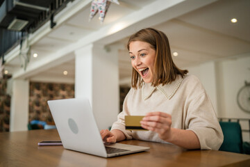 One young business woman holding credit card and shopping online on laptop, modern consumer concept