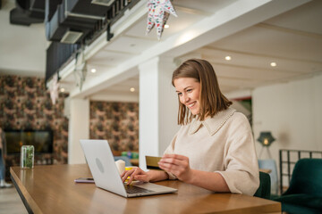One young business woman holding credit card and shopping online on laptop, modern consumer concept